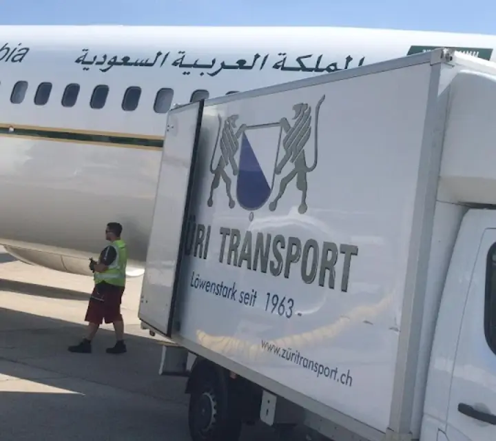 Umzugswagen von Züri Transport neben einem Flugzeug am Flughafen