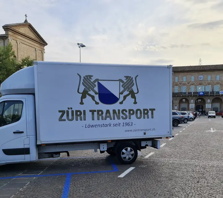 Umzugswagen von Züri Transport auf einem Platz vor historischen Gebäuden