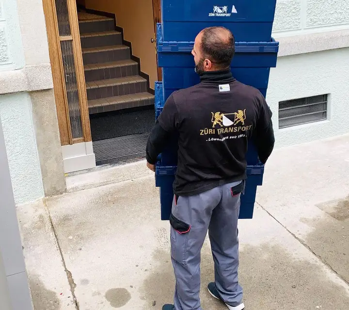 Mitarbeiter trägt Umzugsboxen ins Treppenhaus